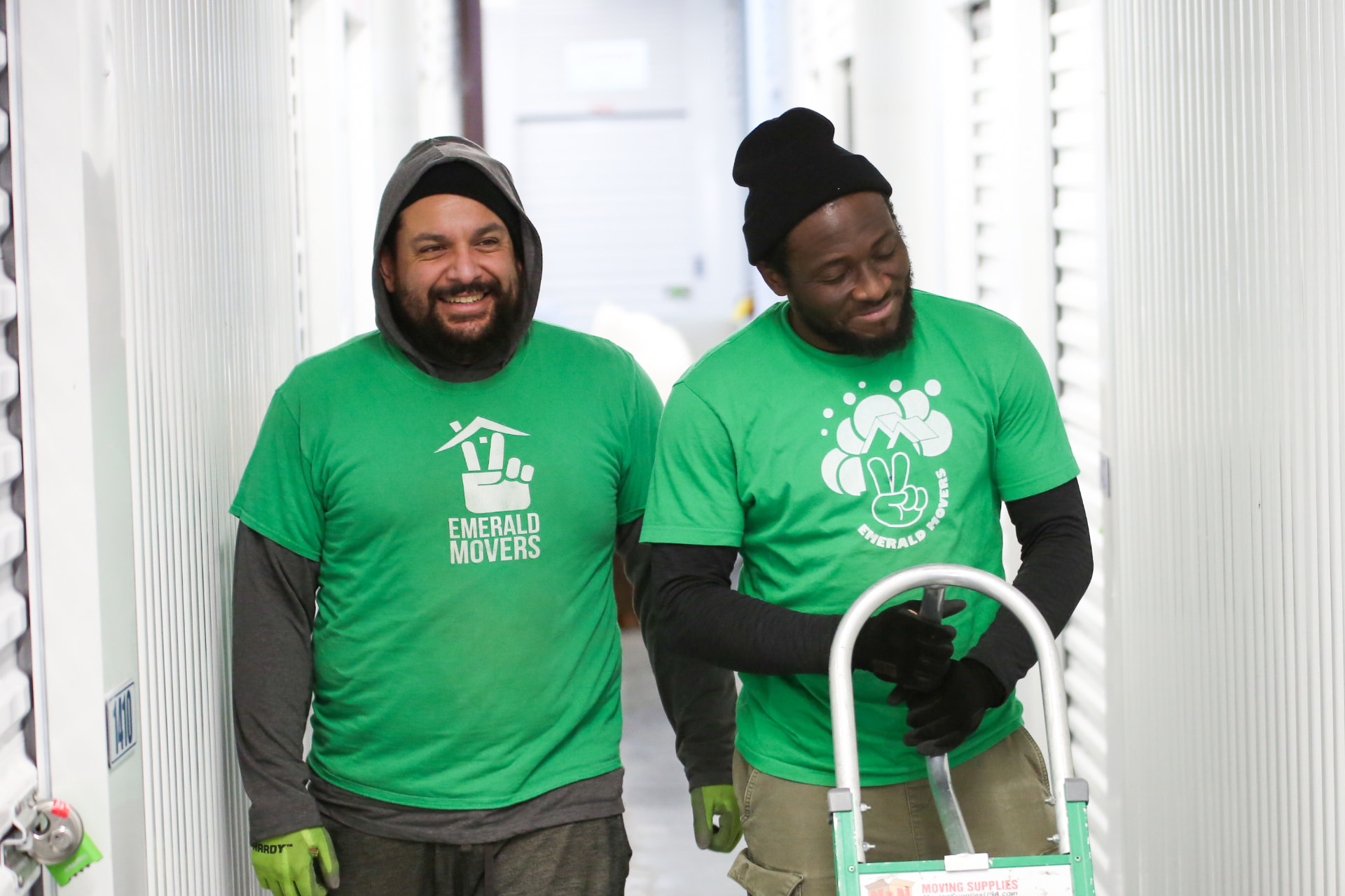 Two Emerald Movers crew members walking through a storage facility hallway