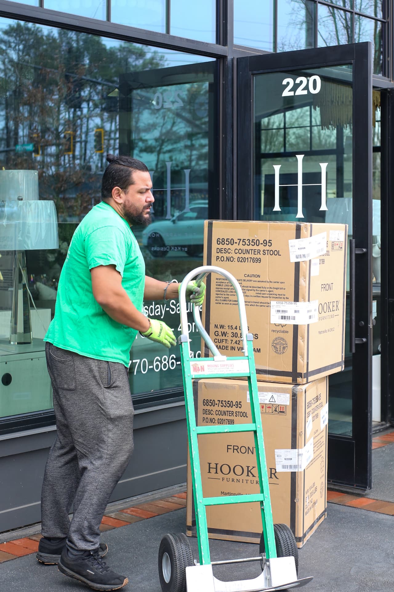 Emerald Movers mover wheeling boxed furniture into a Metro Atlanta showroom on a hand truck