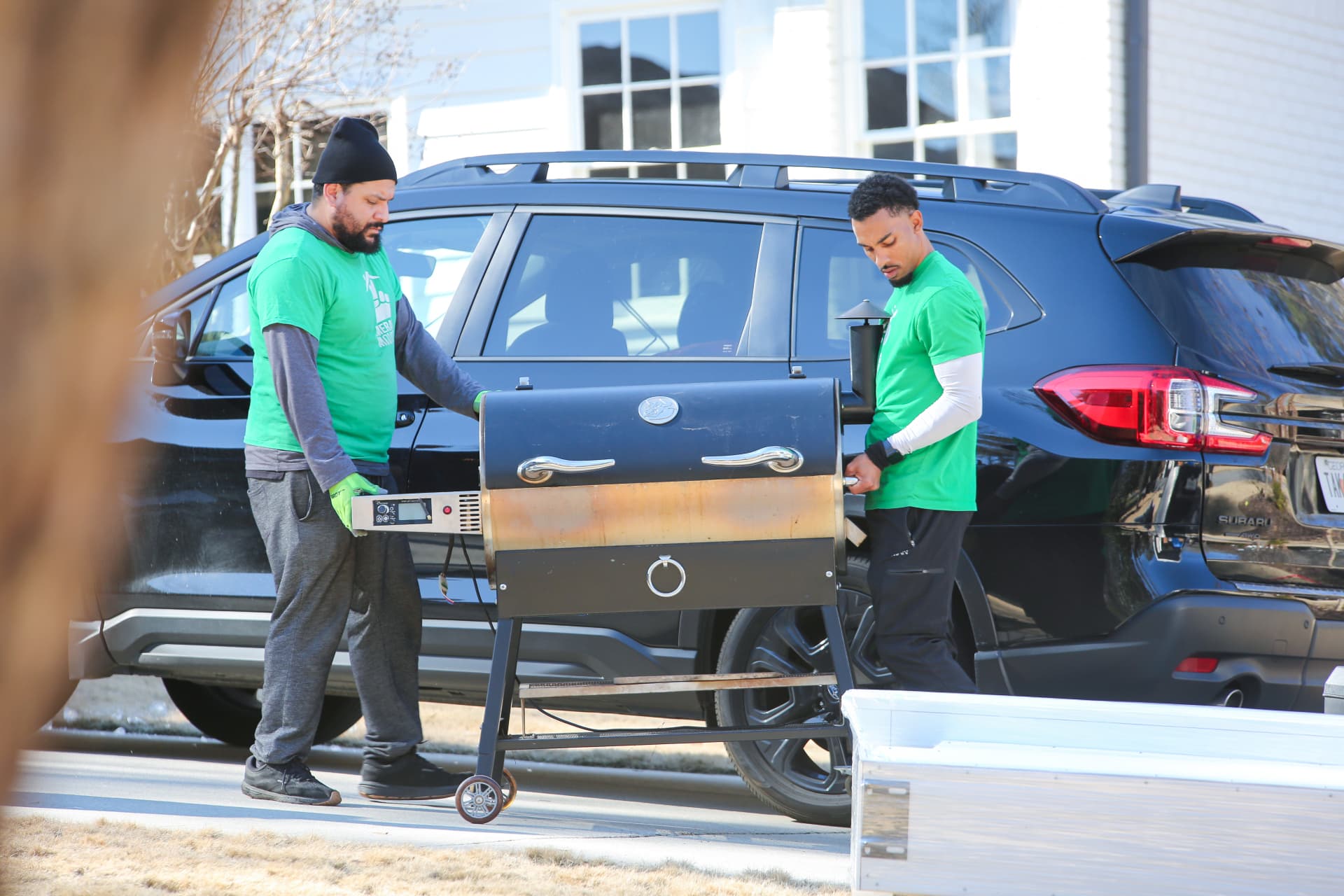 Emerald Movers crew carefully moving a pellet grill out of a driveway